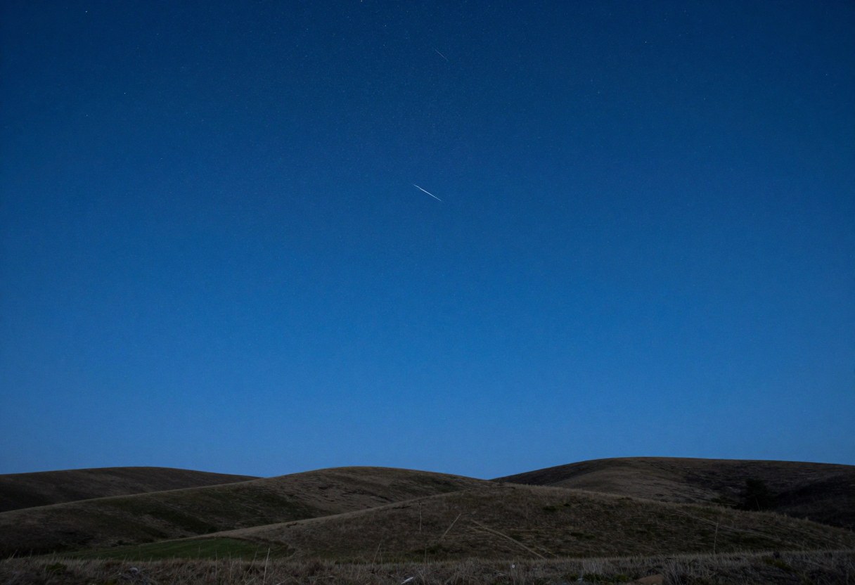 Photo-style AI-generated image of a faint meteor in a deep blue early-evening sky over grassy hills